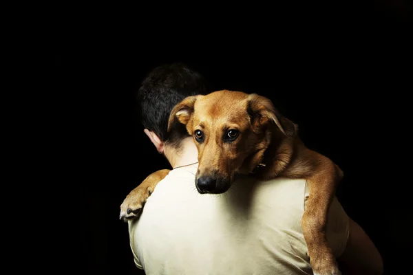 Hund auf den Schultern eines Mannes. Junge hält seinen Welpen auf der Schulter — Stockfoto
