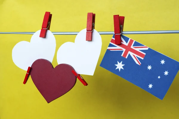 Fehér két hearts - hely a szövegek számára. piros szív és ausztrál zászló lógott csapok (ruhacsipesz) egy sor sárga háttérrel. Ausztrália. Koncepció - kívánja az ünnepekre, tájékoztató szöveg. tónusú színes — Stock Fotó