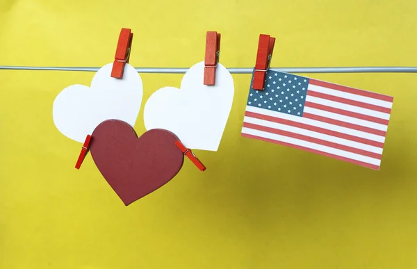 Inimi albe - cameră pentru text, steagul SUA (America) atârnând pe cuie colorate (clothespin) pe o linie pe un fundal albastru. Statele Unite ale Americii. Concept - dorințe pentru sărbători, text de informare. tonifiat colorat — Fotografie, imagine de stoc