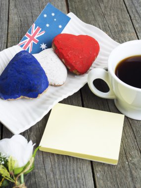 Heart shaped cookies red, white, blue.  cup of coffee (tea), Australia flag - decoration on old wooden table. notebook Happy Australia Day and koala. Sunny morning. Toned colored