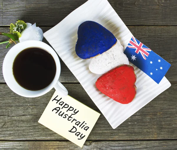 Cookies em forma de coração vermelho, branco, azul. xícara de café (chá), bandeira da Austrália decoração na velha mesa de madeira. notebook Feliz Dia da Austrália e coala. Manhã ensolarada. Cor tonificada — Fotografia de Stock