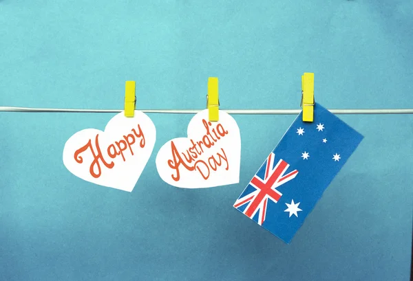 Feiern australischen Feiertag am 26. Januar mit einem fröhlichen Gruß über weiße Herzen, australische Flagge hängt an Wäscheklammern vor rotem Hintergrund. getönte Collage — Stockfoto