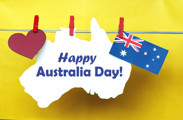 Celebrate Australia Day holiday on January 26 2016 with a Happy Australia Day message greeting written across white Australian maps (red heart) and flag hanging pegs on blue. Toned collage — 图库照片