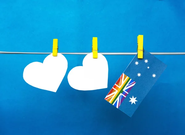 White hearts hanging pegs on yellow. australian flag with rainbo — Stockfoto