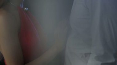 Kırmızı elbiseli bir kadın nazikçe sevgili erkeğinin gömleğini çıkarıyor.