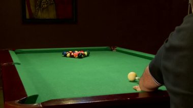 Bardaki adam bilardo oynuyor. Adamın biri bilardo topuna ıstakayla vuruyor ve top deliğe düşüyor.