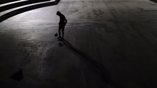 街の背景を背景に夜サッカーをする男のシルエット — ストック動画