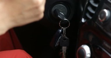 Arabanın anahtarlarını sokete takıp motoru çalıştıran bir kadının yakın plan çekimi. Araba anahtarlı bir adam. Ateşleme arabası.