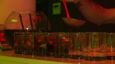 Panç kasesi. Barmen bardaklara portakal kokteyli dolduruyor.. 