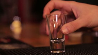 Barmen votka dolduruyor. Erkekler bir bardak votka içer ve bardakları barın üstüne koyar..