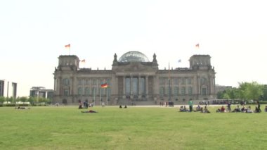 Berlin, Almanya - Nisan 2014 - Reichstag Binası, İnsanlar yürüyor, bisiklete biniyor, çimenlerde oturuyor ve dinleniyor