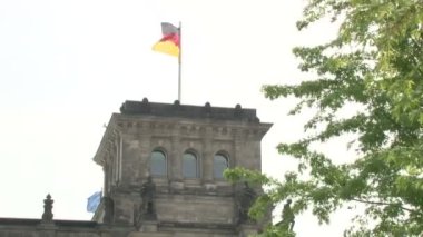 Berlin 'deki Reichstag binasında heykeller, taş heykeller ve levhalar, binada Alman bayrakları, çatıda cam kubbe.