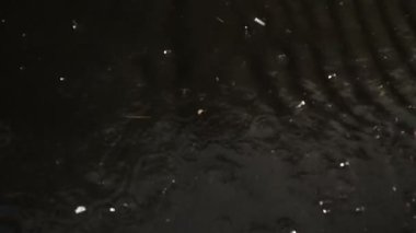 Şiddetli yağmur suları yolda akar ve deliklerle metal kapağa düşer. Yakın çekim - 4K