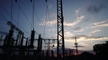 Gün batımında bir elektrik santrali ve elektrik şebekesi manzarası. Kirlilik ve iklim değişikliği kavramı. Güzel sarı ışıkla gün batımı zamanı. 