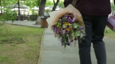 Gücenmiş adam bir buket çiçek ve hediyeyi çöpe atar..