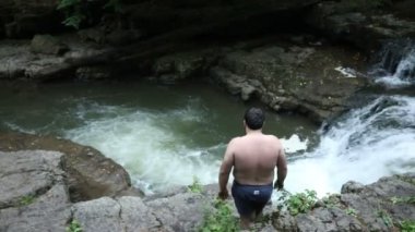 Adam ormandaki Şelale 'de Nehir Havuzu' na atlamış. Uçurumdan atlayıp nehrin kenarındaki şelaleye atlayan bir adam.. 