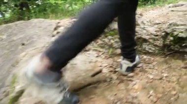 Sırt çantalı bir adam ve yeşil bir ormanda yürüyüş yolu boyunca giden bir kamera. Sırt çantalı bir turist Dağ Ormanı 'ndaki Taş Patikası boyunca aşağı gidiyor. Kayalık dağ ormanlarında yürüyüş yapan bir adam.