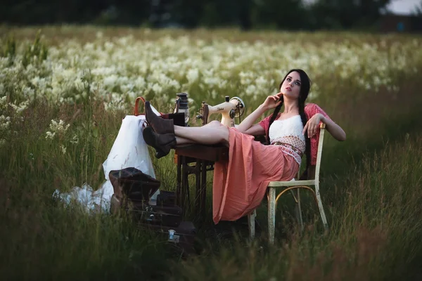 Young girl with long dark hair standing near a table in the summer field. — Stock Photo, Image