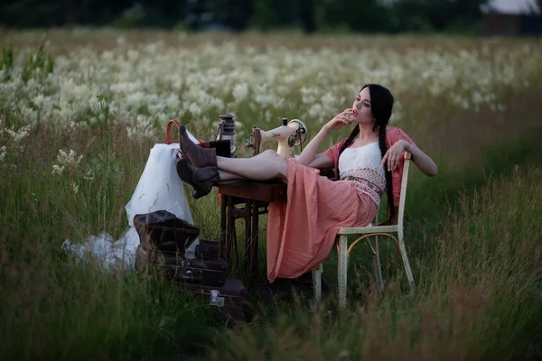 Young girl with long dark hair standing near a table in the summer field. — Stock Photo, Image