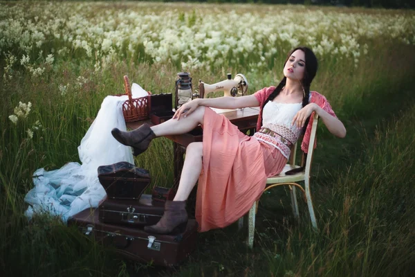 Chica joven con el pelo largo y oscuro de pie cerca de una mesa en el campo de verano . —  Fotos de Stock