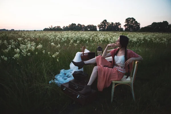 Young girl with long dark hair standing near a table in the summer field. — Stock Photo, Image