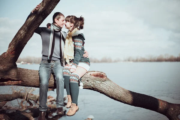 Romantický pár sedící na větvi poblíž vody. — Stock fotografie