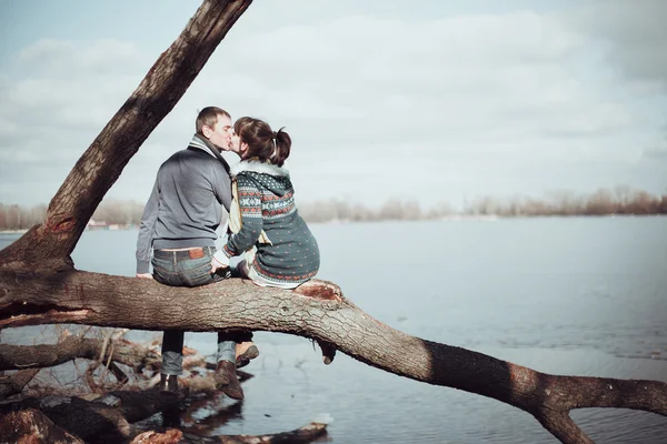 Романтическая пара, сидящая на ветке у воды . — стоковое фото