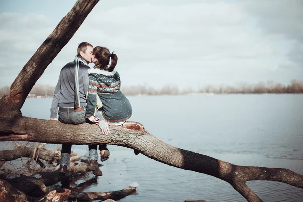 Pareja romántica sentada en una rama cerca del agua . — Foto de Stock