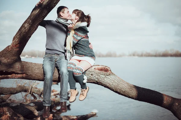 Pareja romántica sentada en una rama cerca del agua . — Foto de Stock