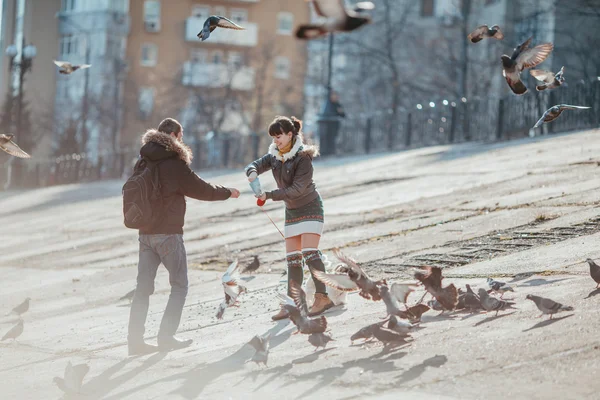 Paar füttert Tauben in der Stadt. — Stockfoto