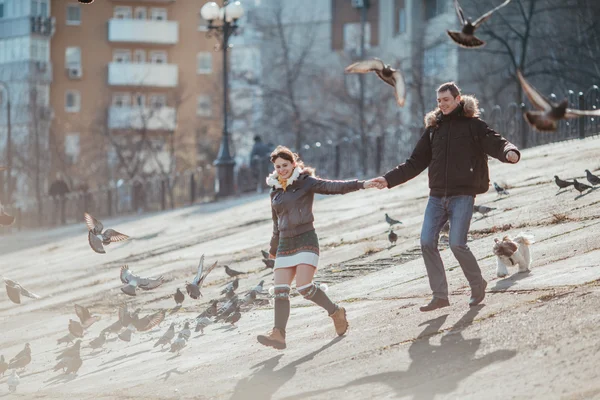 Coppia in esecuzione con piccioni in città . — Foto Stock