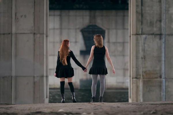 都市の橋の下で一緒に手を取り合って二人の女の子. — ストック写真