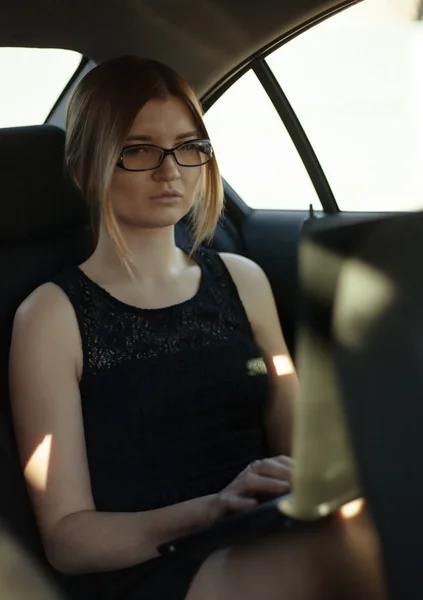 Geschäftigkeit mit Brille am Laptop auf dem Rücksitz. — Stockfoto