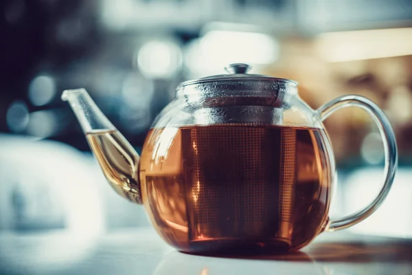 Скляний чайник з гарячим чаєм на кухонному столі . — стокове фото