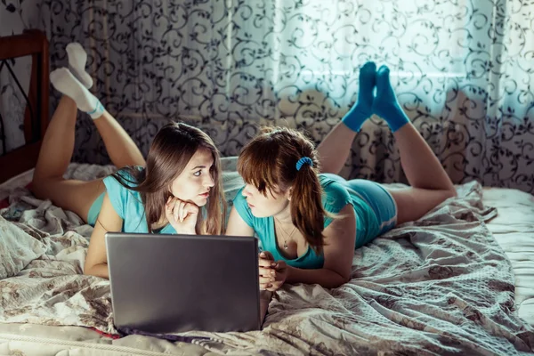 ブルーの t シャツに二人の女の子のベッドの上のラップトップを使用して. — ストック写真
