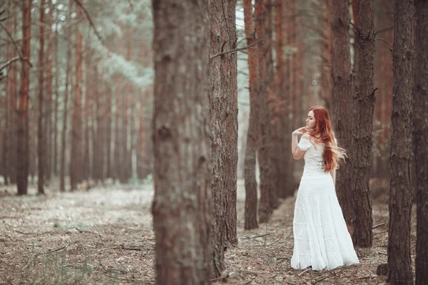 Menina de gengibre em vestido branco andando na floresta de pinheiros . — Fotografia de Stock