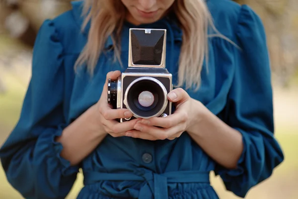 Menina em vestido azul vintage segurando câmera de formato médio antigo . — Fotografia de Stock