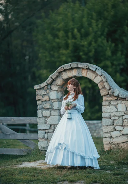 Schönes Mädchen in weißem Vintage-Kleid, das in der Nähe eines alten Steinhauses spaziert. Vintage-Brautkonzept — Stockfoto