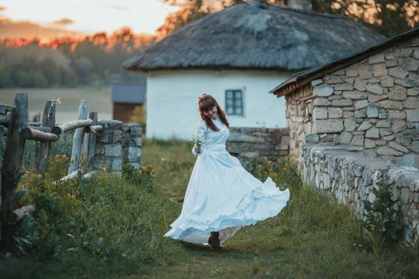 Hermosa chica en vestido vintage blanco caminando cerca de la antigua casa de piedra. Concepto nupcial vintage — Foto de Stock