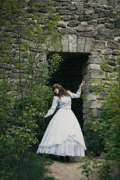 Beautiful girl in white vintage dress walking near ancient stone house. Vintage bridal concept — Stock Photo, Image
