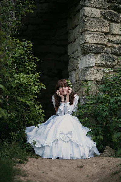 Belle fille en robe vintage blanche marchant près de l'ancienne maison en pierre. Concept de mariée vintage — Photo