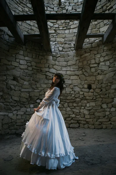 Красивая девушка в белом винтажном платье ходить возле древнего каменного дома. Винтажная свадебная концепция — стоковое фото