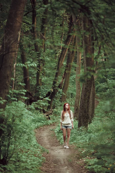 Menina ruiva jovem caminhando através da floresta verde fresca. Conceito de turismo . — Fotografia de Stock