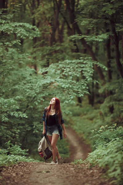 Young redhead girl walking through fresh green forest. Tourism concept. — Stock Photo, Image