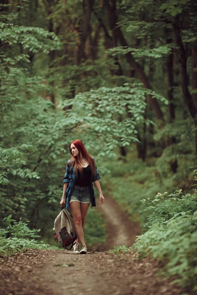 Young redhead girl walking through fresh green forest. Tourism concept. — Stock Photo, Image