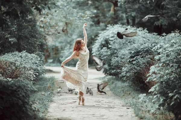 Chica joven en hermoso vestido y zapatos puntiagudos bailando en la calle con palomas voladoras . —  Fotos de Stock