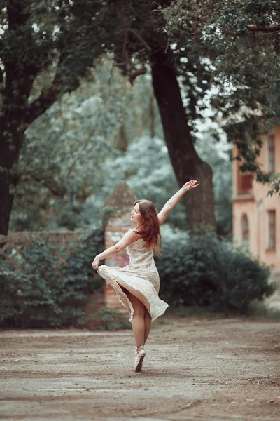 Young girl in beautiful dress and pointe shoes dancing on the street. — Stock Photo, Image