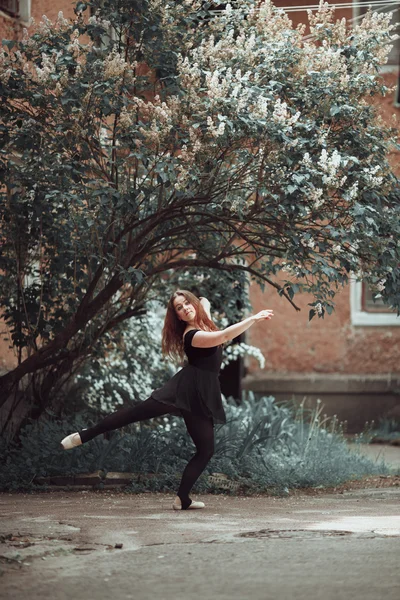 Jong meisje in een mooie jurk en pointe-schoenen dansen op straat. — Stockfoto