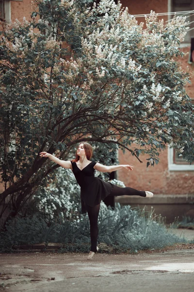 Jong meisje in een mooie jurk en pointe-schoenen dansen op straat. — Stockfoto