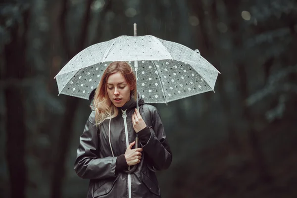 Chica joven caminando a través de un bosque lluvioso con paraguas . —  Fotos de Stock